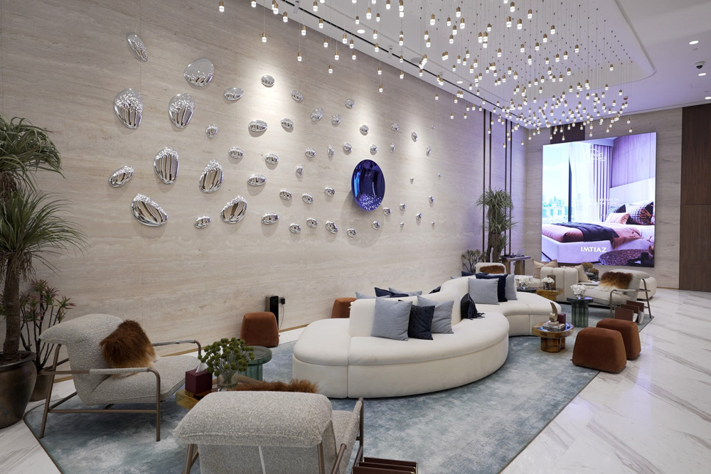 Beach Walk Residence Modern lobby featuring a round sofa, decorative wall art, plants, and a large screen displaying a bedroom.
